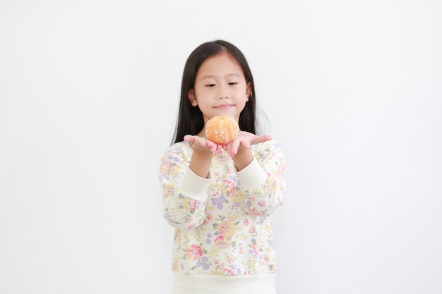 Asian girl holding peeled orange fruit on white