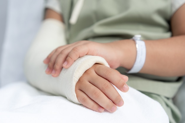 Asian girl in hospital lying in bed with a broken arm back from surgery