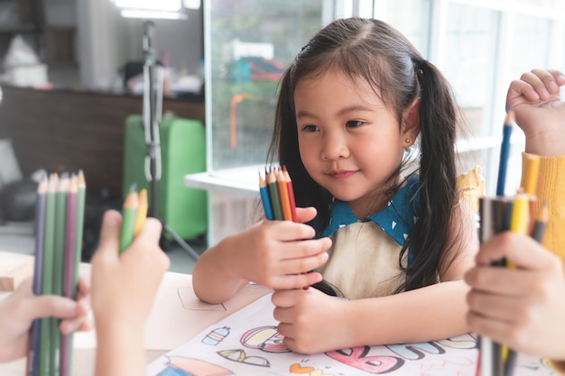 Asian girl is drawing in kindergarten art classroom