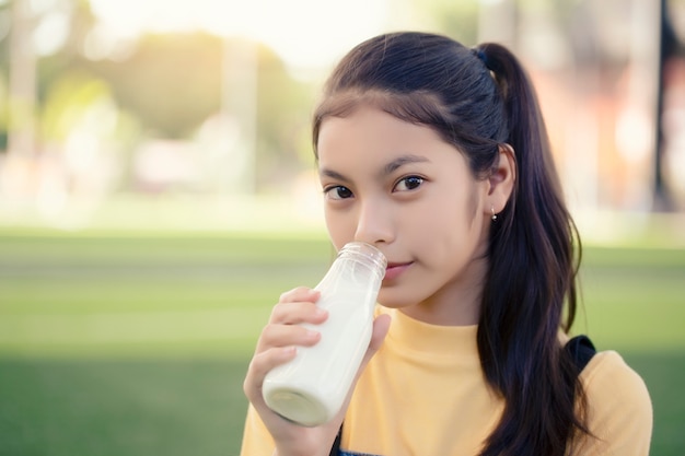 An Asian girl is drinking a delicious bottle of milk.