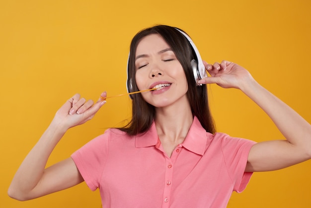 Asian girl is posing with gum, headphones isolated