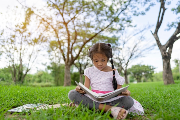 アジアの女の子は公園で本を読んでいます。