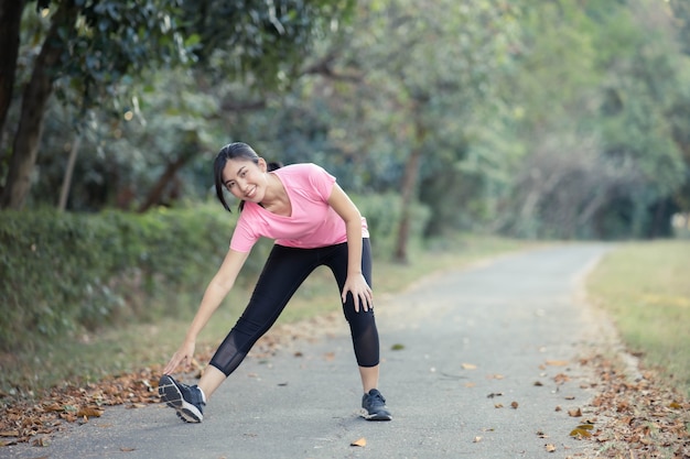 Asian girl is stretching her body warm muscles before going out for a run at the park