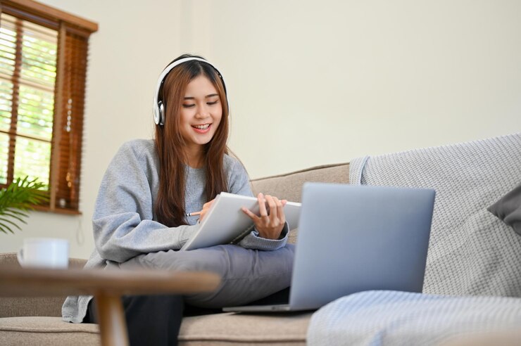 Photo アートワークをスケッチしながらヘッドフォンで音楽を聴くアジアの女の子