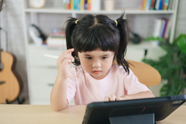 Asian girl looking and touch on white screen at the tablet
screen attentively overstimulated children concept too much screen
time cute girl watching videos while tv internet addiction
concept