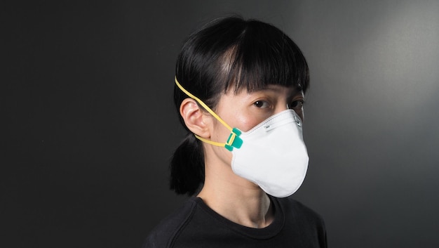 Asian girl in a mask on a black background in Coronavirus Quarantine situation