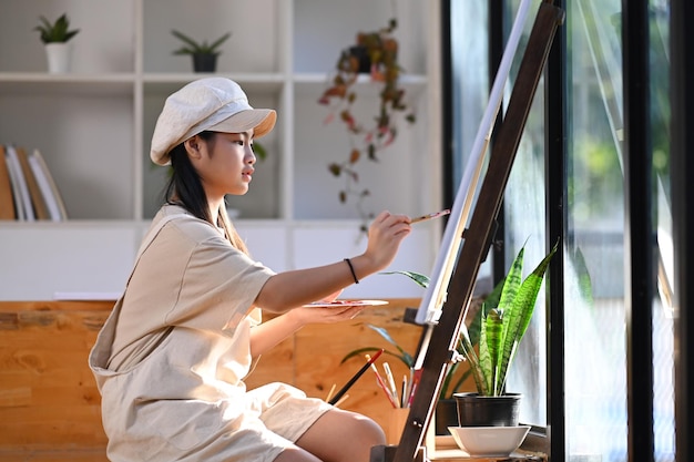 Азиатская девушка рисует картину акварелью в художественном классе