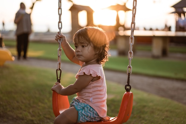 ブランコで遊んで、公園で楽しんでいるアジアの女の子