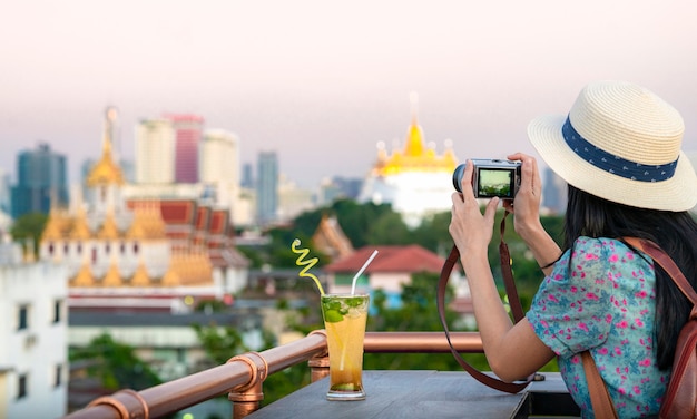 방콕 시내의 옥상 바에서 휴식을 취하고 로하 프라 사트의 관점을 즐기는 아시아 소녀