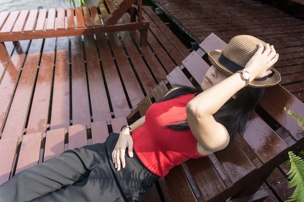 Asian girl in the resort in red clothes and hat sleep on bed pool.