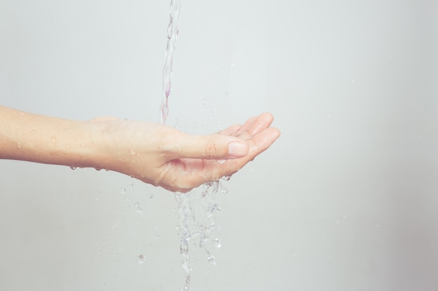 アジアの女の子の手が水で飛び散っている。白い背景に