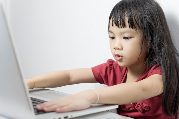 Asian girl seriously working on a laptop computer. Practicing using technology devices. 