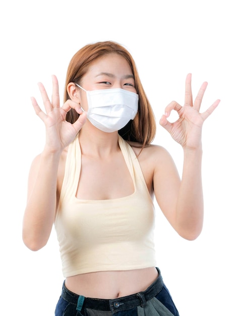 Asian girl shows ok sign with hands wearing protective face mask for protection during the quarantine Coronavirus covid19 outbreak on white background protect spread Covid19