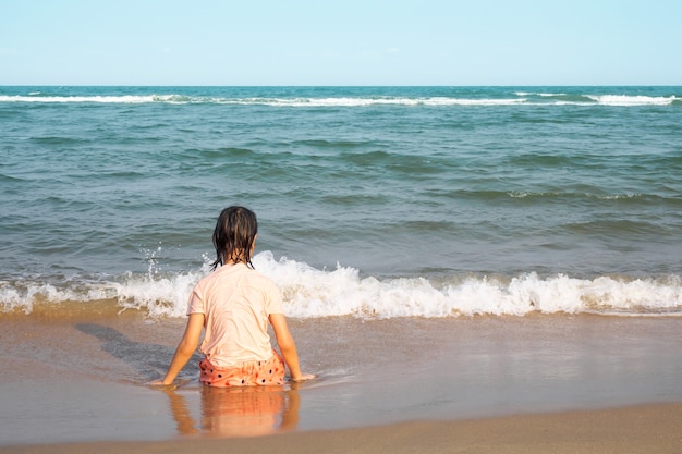 Foto ragazza asiatica che si siede sulla spiaggia