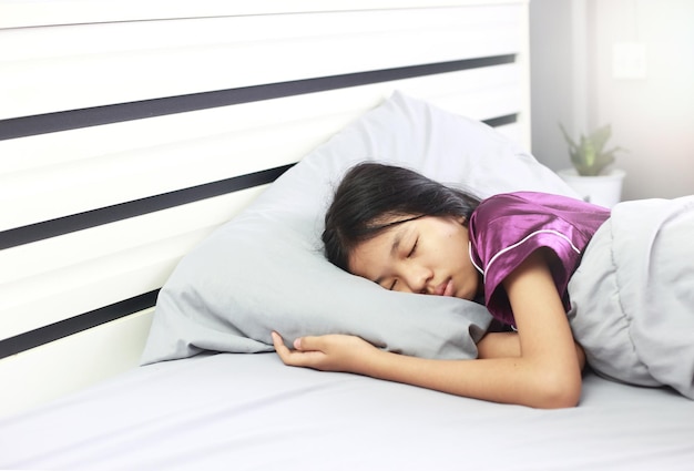 병 중에 자고 있는 아시아 소녀 그녀는 창백한 얼굴을 하고 침대와 담요에서 잠을 자고 있습니다. 나쁜 건강은 휴식이 필요합니다
