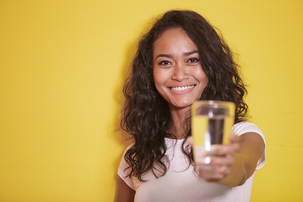 Ragazza asiatica che sorride mentre offre un bicchiere di acqua minerale