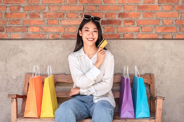 asian girl smiling with holding credit card and shopping bags enjoying in shopping relax expression