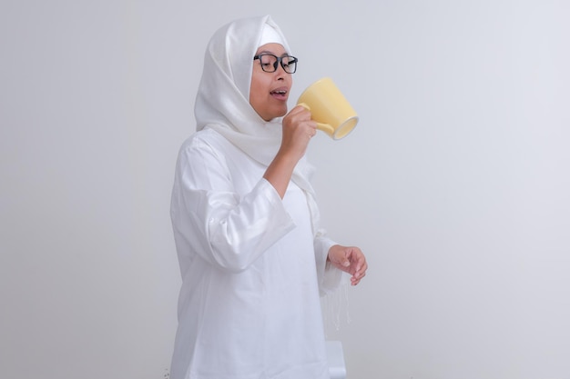 Photo asian girl standing and drinking water to break her fast during ramadan month