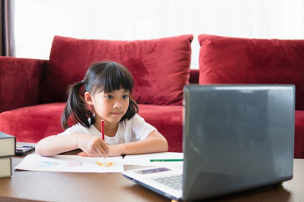 アジアの女子学生のオンライン学習クラスは、自宅のラップトップでオンラインで勉強します。