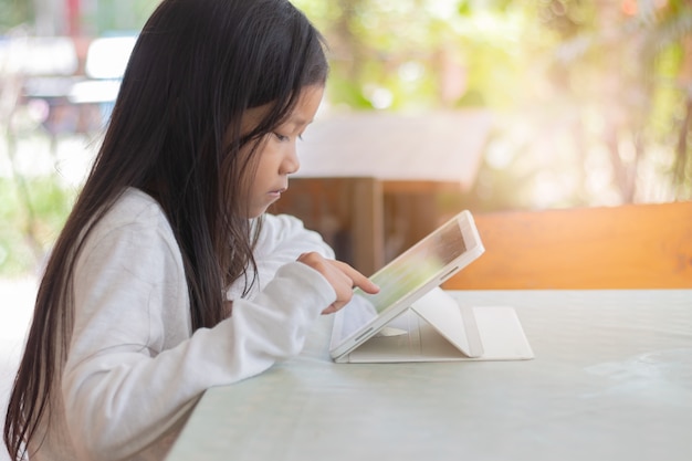 アジアの女子学生。幸せな陽気な若いアジアの女の子笑顔とタプレットを使用して