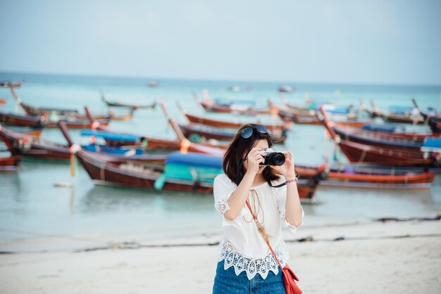 アジアの女の子がビーチで写真を撮る