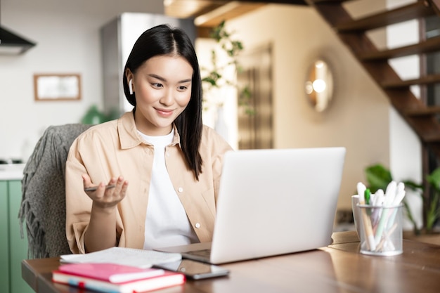 Photo asian girl talks on video chat with laptop smiling and having conversation using online computer app...