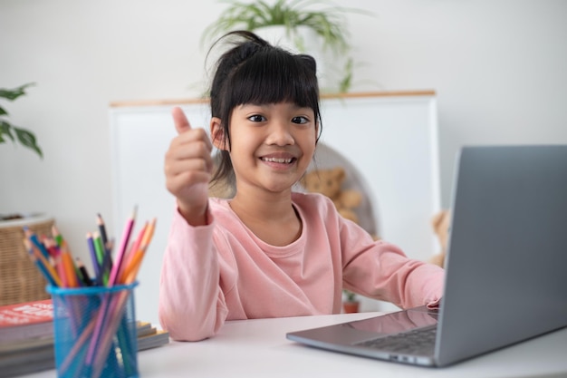 Photo asian girl using laptop computer for online study homeschooling during home quarantine. homeschooling, online study, home quarantine, online learning, corona virus or education technology concept