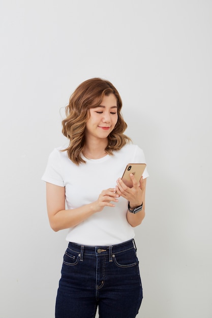 Asian girl using smartphone on grey wall