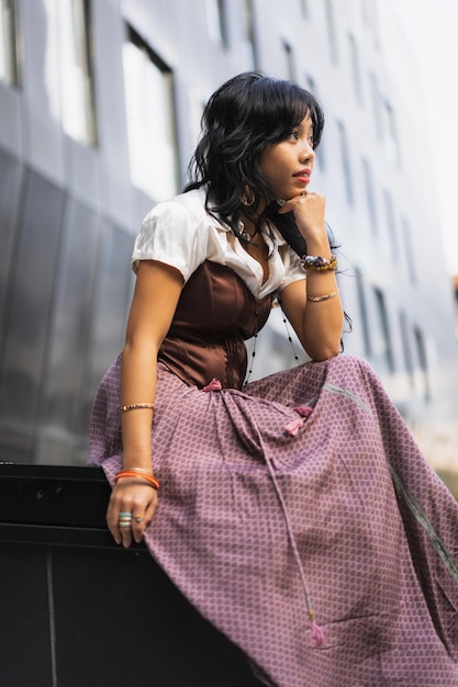 An Asian girl in a vintage Asian traditional long dress sitting and thoughtful