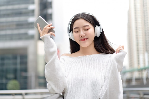 사진 아시아 소녀는 헤드폰을 착용하고 눈을 가진 음악 스트리밍 스트리밍 폐쇄