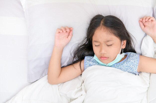 Asian girl wearing protective masks on bed