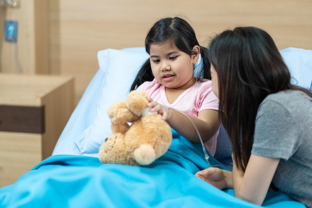 Asian girl with a broken arm wearing a cast on the hospital bed with her mother