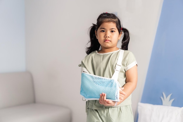 Asian girl with a broken arm wearing a cast on the hospital bed