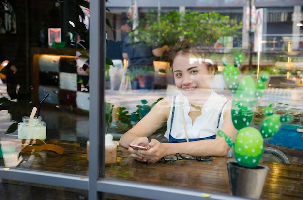 Photo asian girl with smile face in cafe holding smartphone