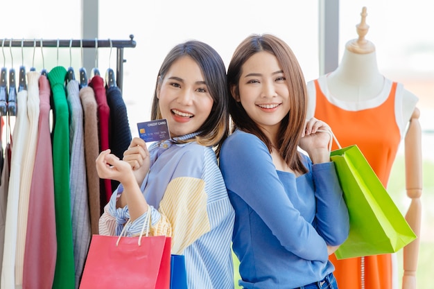 Asian girls enjoy shopping with cashless credit card payment with friend happy moment fun in sale shop together.