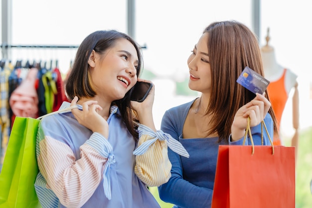 Le ragazze asiatiche si divertono a fare shopping con il prestito telefonico con carta di credito senza contanti dal pagamento del callcenter con un amico felice momento divertente nel negozio di vendita insieme.