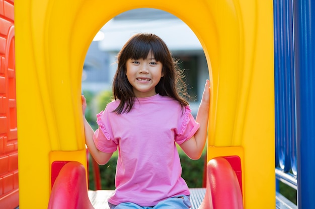 すべり台で遊ぶアジアの女の子が遊び場