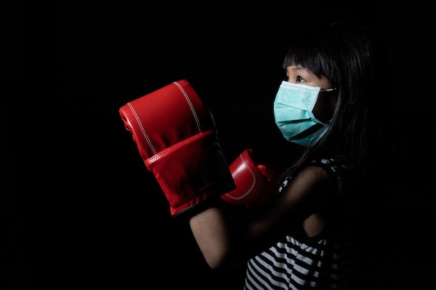 Le ragazze asiatiche indossano maschere per proteggersi dai virus e indossano guantoni da boxe per simboleggiare i virus da combattimento come coronavirus