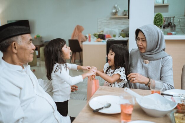 Asian grandparents giving a present to grandchildren during eid mubarak celebration at home