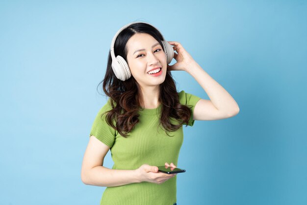 Портрет девушки азиатский кузнечик слушает музыку, изолированные на синем фоне