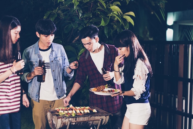 Asian group of friends having outdoor garden barbecue 