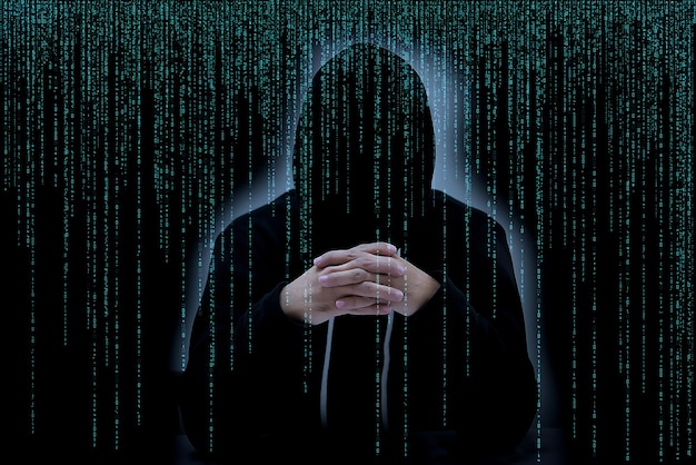 Азиатский хакер в черном капюшоне с матричным фоном
