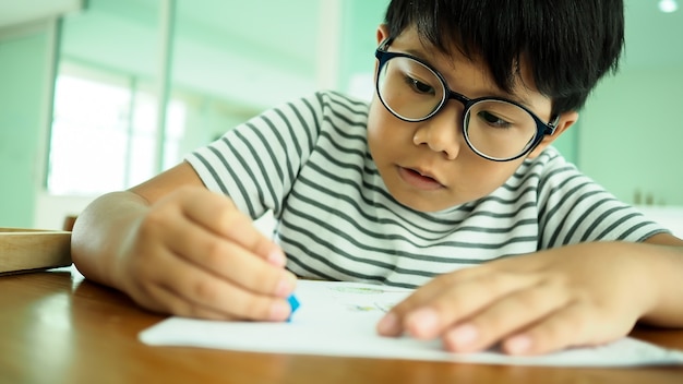 Asian handsome boy drawing and coloring in classroom