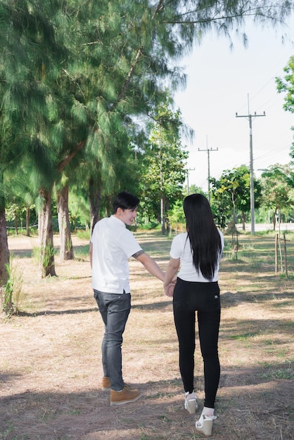 Азиатский красивый мужчина держит женщину за руку для прогулки вместе