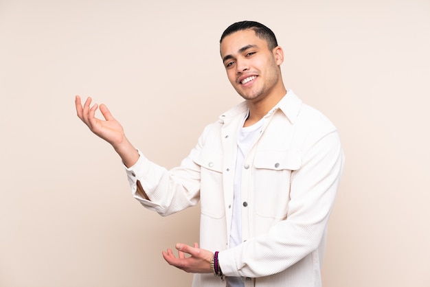 Asian handsome man over isolated background extending hands to the side for inviting to come