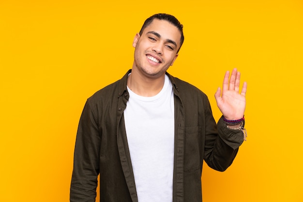 Asian handsome man isolated on yellow background looking to the side and smiling