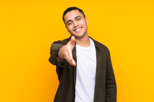 Asian handsome man isolated on yellow background pointing up and surprised