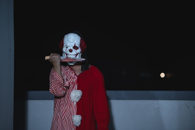 Asian bell'uomo indossare maschera da clown con arma alla scena notturnahalloween festival concepthorror spaventoso foto di un assassino in panno arancionepersonaggio pagliaccio malvagio