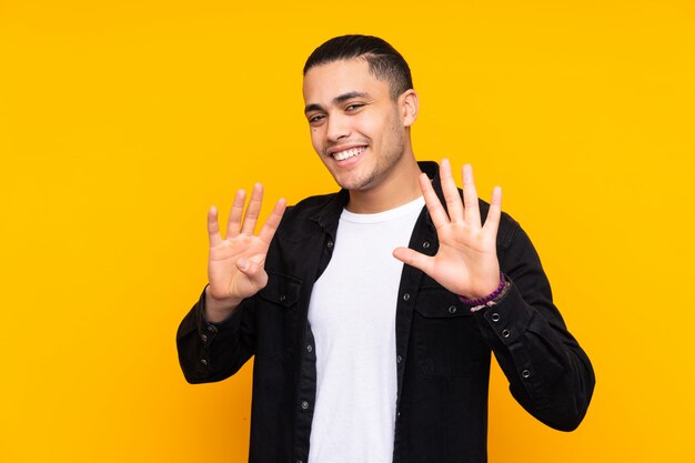 Asian handsome man on yellow wall covering eyes by hands and smiling