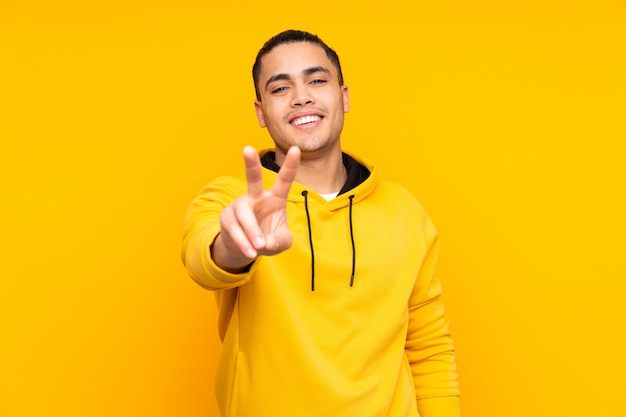 Asian handsome man on yellow wall with arms crossed and looking forward